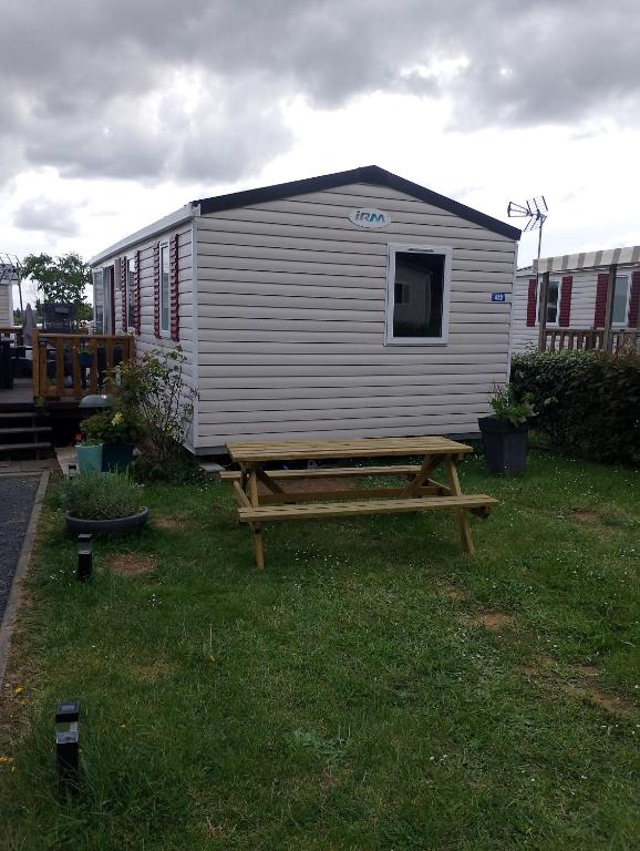 a shed with a picnic table in the grass at Location mobil home in Litteau