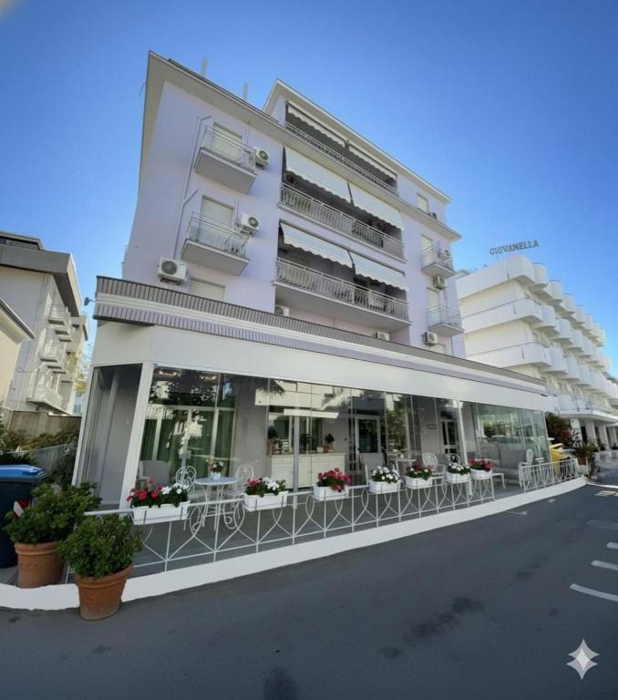 a white building with tables and chairs in front of it at Hotel Ornella in Bellaria-Igea Marina