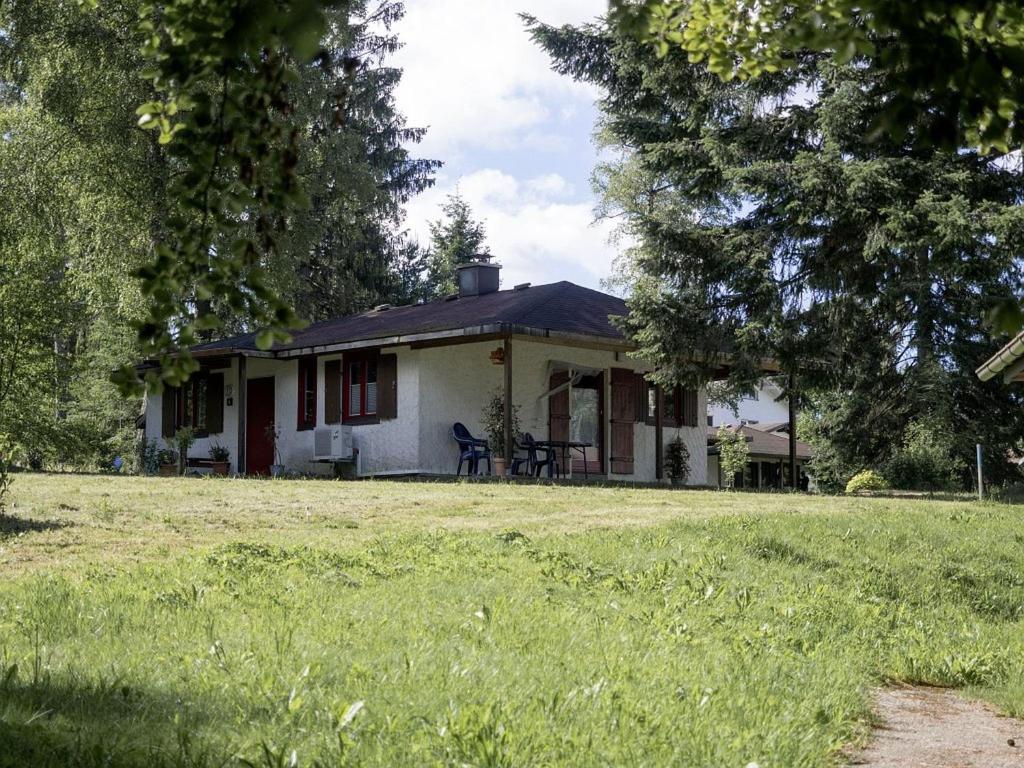 une petite maison blanche avec une cour et des arbres dans l'établissement Ferien- & Freizeitpark Grafenhausen, à Grafenhausen