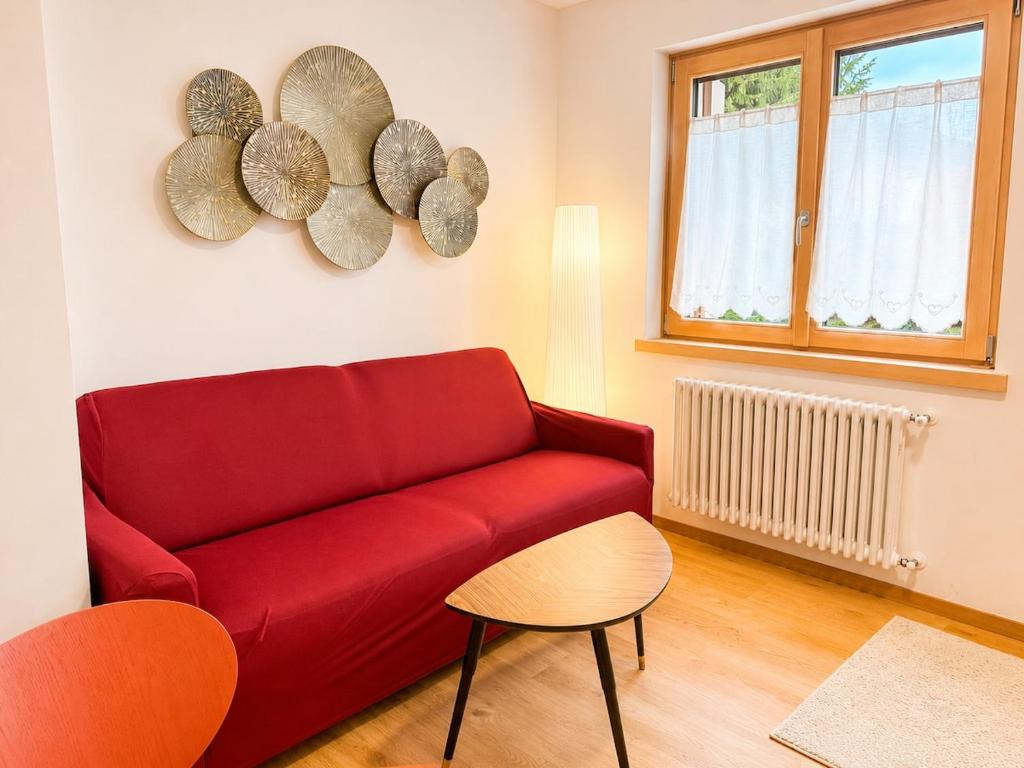 a living room with a red couch and a window at Rosso Betulle, Free Park and Ski room in Camporosso in Valcanale