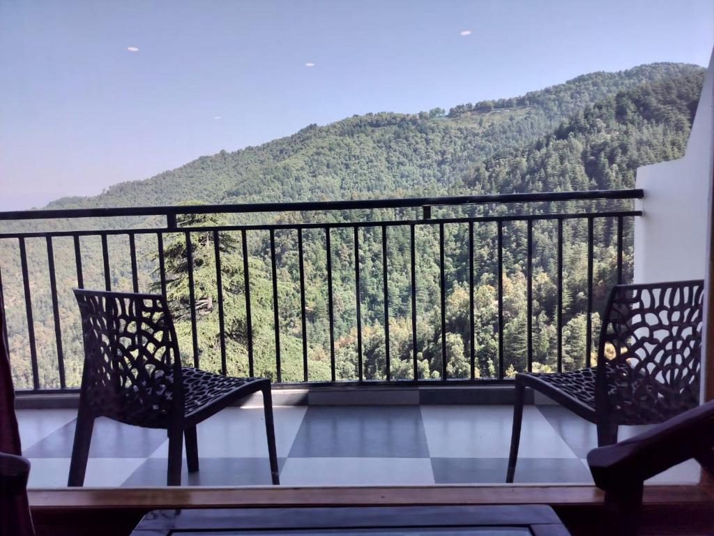 two chairs on a balcony with a view of a mountain at Hotel Summer Hill in Chail
