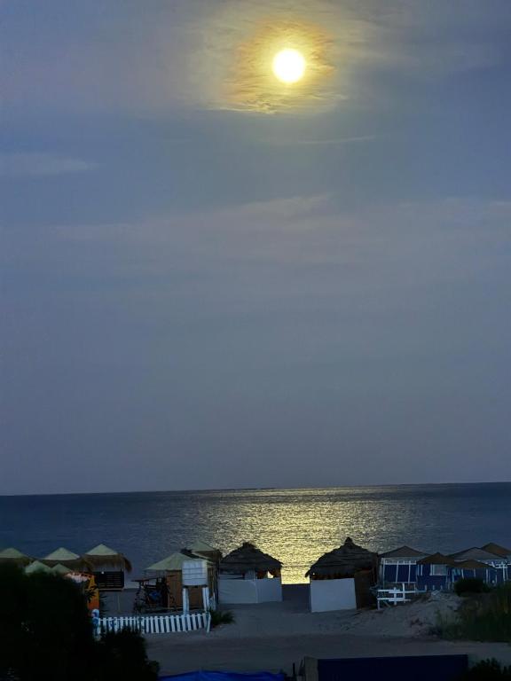 a view of the beach at night with a full moon at Villa Pieds dans l eau entre Lagune et Montagne in Ghār al Milḩ