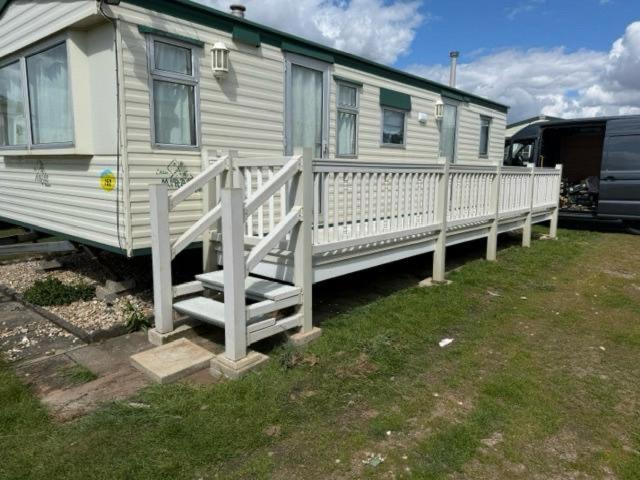 a white rv with a porch and a fence at Ingoldmells golden sands plot 152 in Ingoldmells