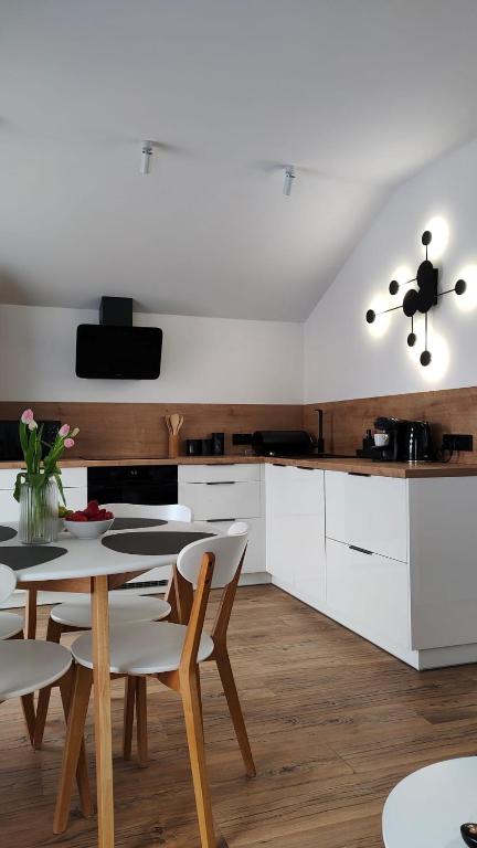 a kitchen with white cabinets and a table and chairs at Apartament DobraNocka in Ściegny
