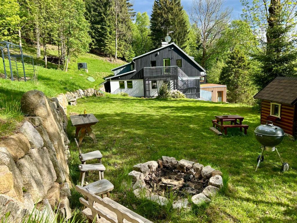 a house with a fire pit and a grill in a yard at Jizerína in Bedřichov