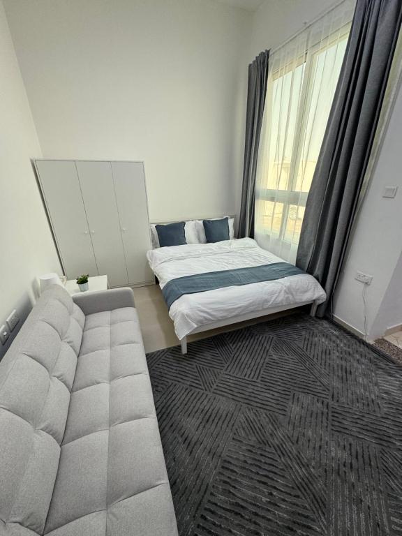 a bedroom with a bed and a couch and a window at روز للاستديوهات المفروشة in Abu Dhabi