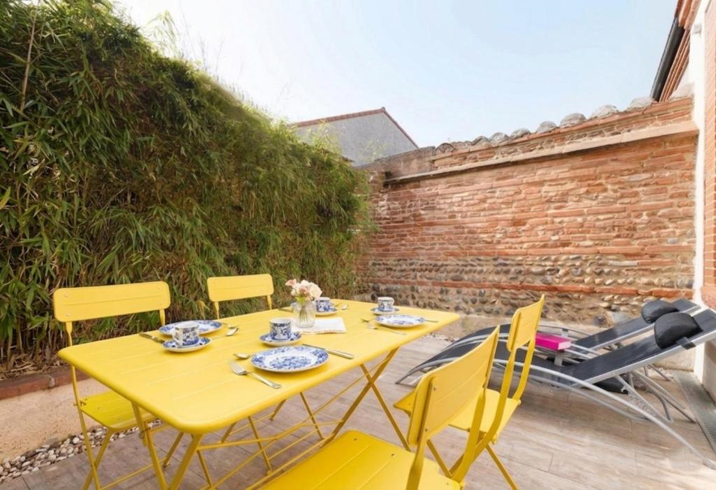 a yellow table and chairs on a patio at Beautiful House avec AC climatisation - terrasse privée - Côté pavé centre-ville Toulouse in Toulouse