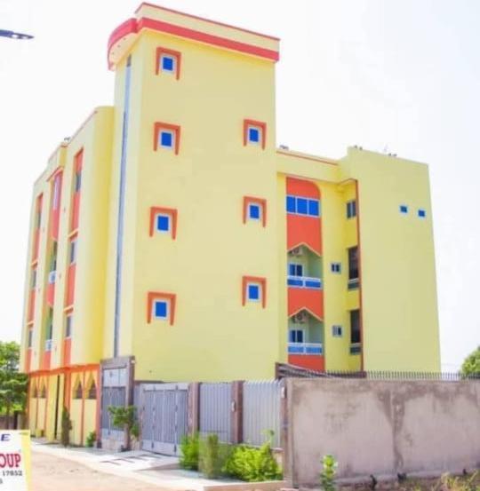 a large yellow building with red and blue windows at Résidence Hôtel KOUNAF GROUP in Parakou