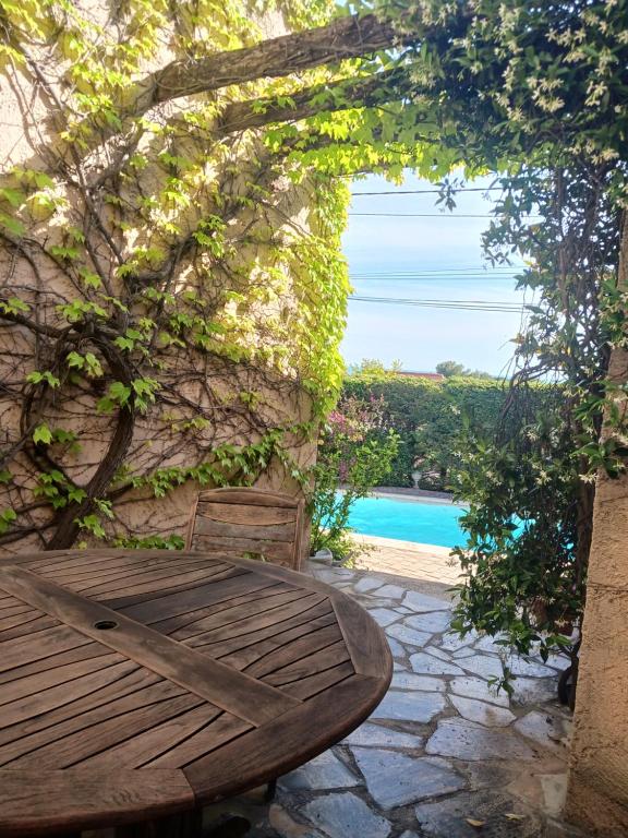 a wooden bench sitting next to a stone wall with a pool at La Villa des Restanques in Carry-le-Rouet