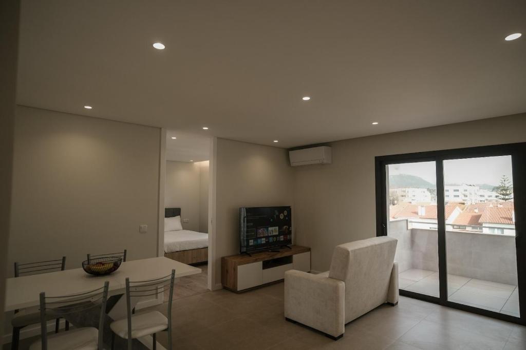 a living room with a table and chairs and a television at Alba Esposende - Balcony Apartment in Esposende