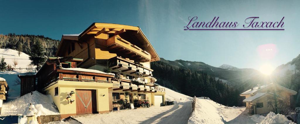 a building in the snow with the sun behind it at Landhaus Taxach in Saalbach Hinterglemm