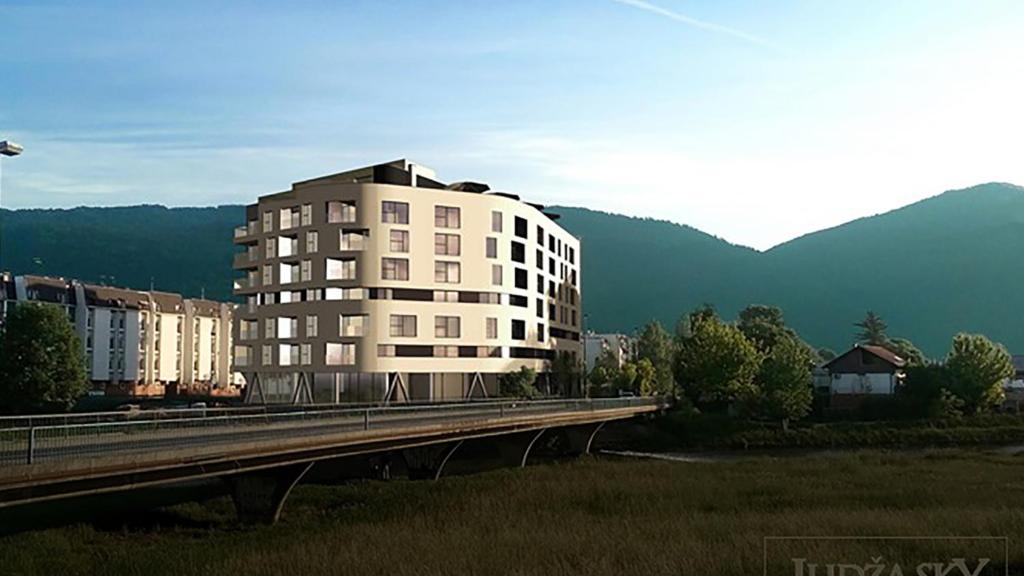 a tall white building next to a bridge with mountains at SKY Apartment in Sarajevo