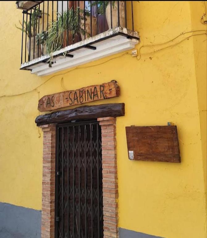 a yellow building with a door and a sign and a balcony at Casa Sabinar in Navajas