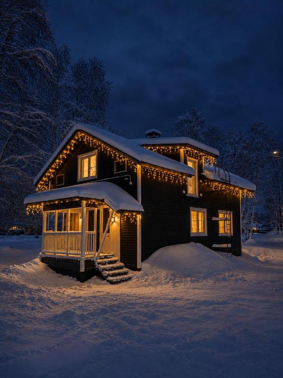 a house covered in snow at night with lights at Northern lights Ivalo Stay in Ivalo