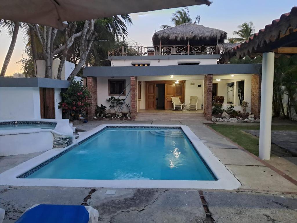 a villa with a swimming pool in front of a house at Villa Lya in Juan Dolio