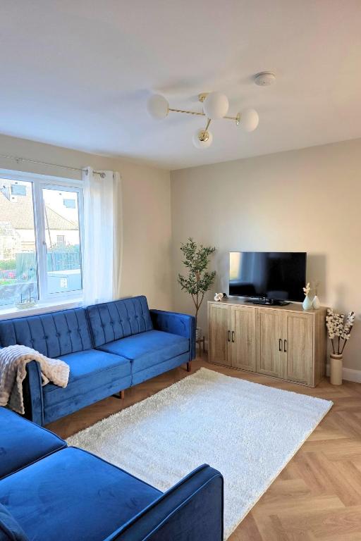 a living room with a blue couch and a tv at Coastal Cottage NC500 in Castletown