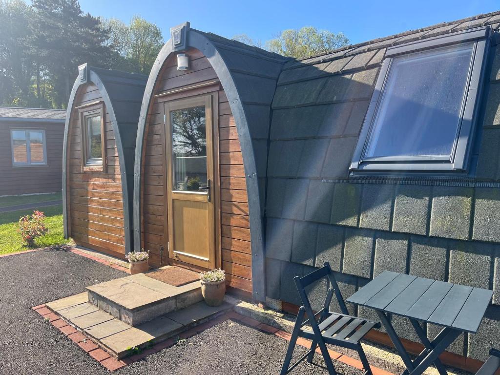 a tiny house with a table and a bench at Hedgehog Glamping Pod in Leighton