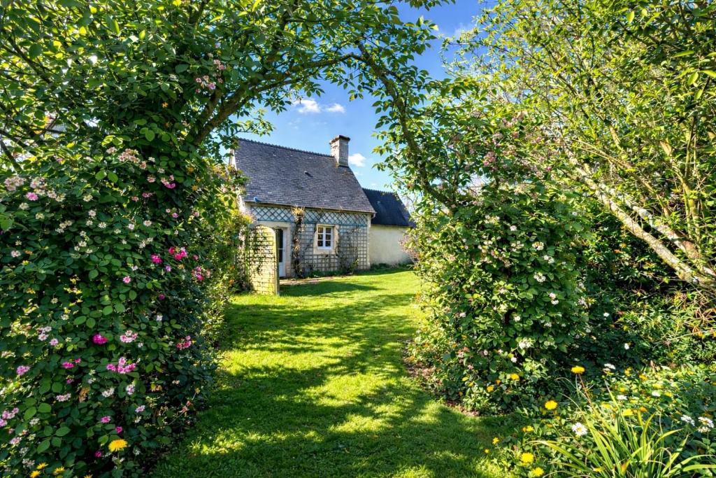 an archway leading to an old house with roses at Charmant logement dans un écrin de verdure in Le Manoir