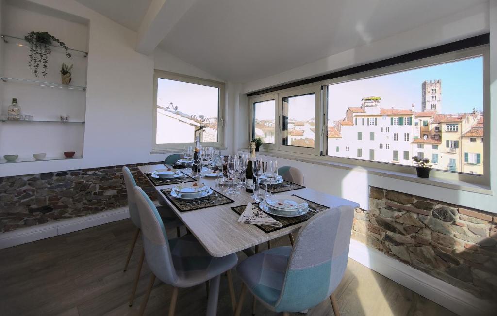 a dining room with a table and chairs and windows at Attico di Cesare Luxury Piazza Anfiteatro Lucca in Lucca