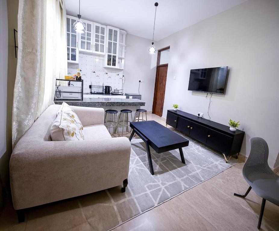 a living room with a couch and a table and a kitchen at Rosewood Cozy homes in Mbeya