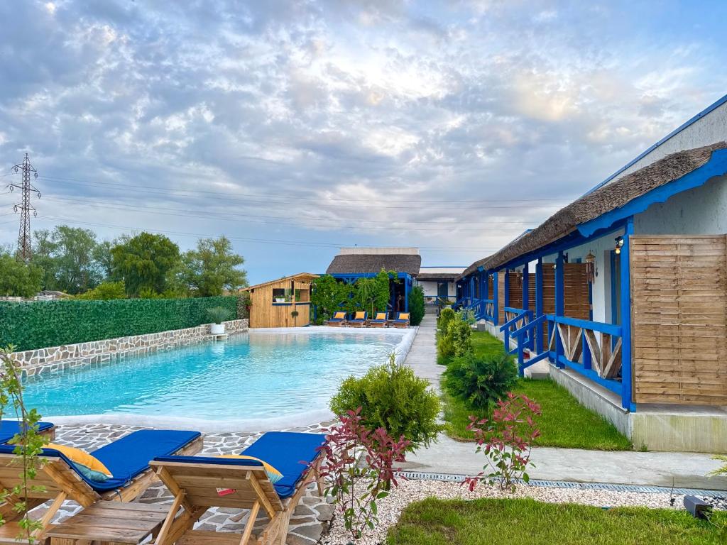 a swimming pool with chairs and a house at Delta Land Bungalows in Crisan