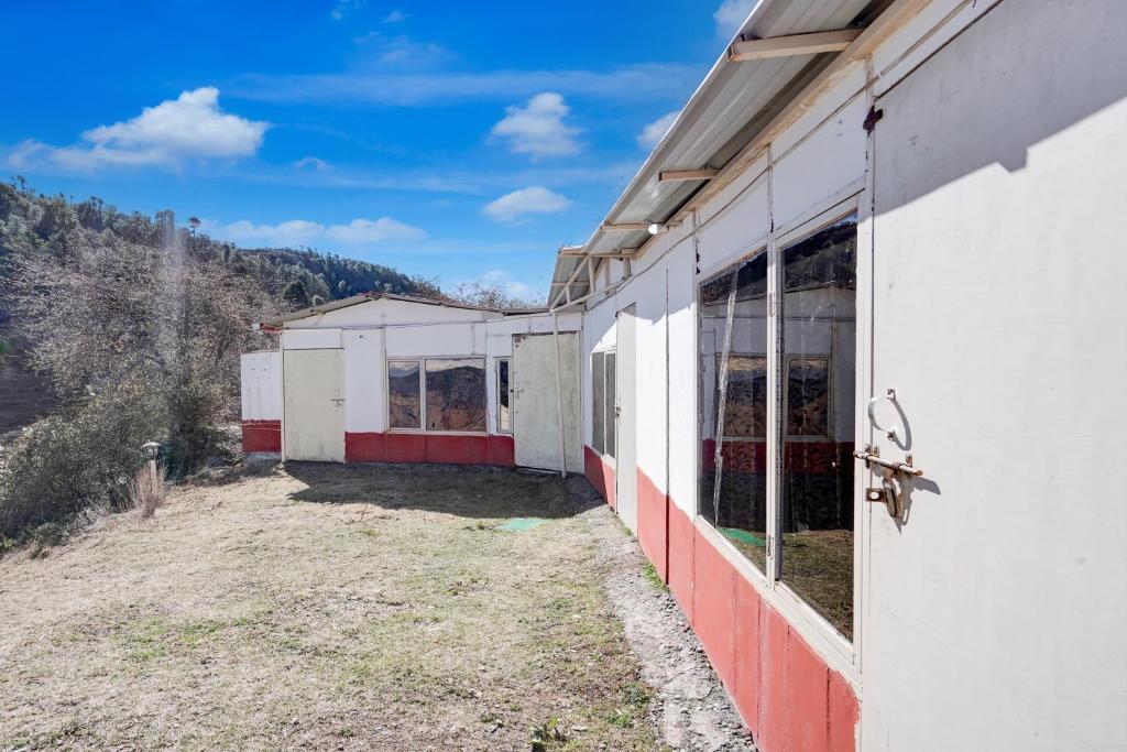 a side view of a building with mountains in the background at hotel O snow breeze adventures in Dhanaulti
