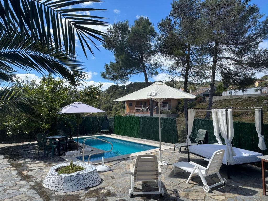 a swimming pool with chairs and a table and a house at Villa Maria Mercedes in Olesa de Bonesvalls