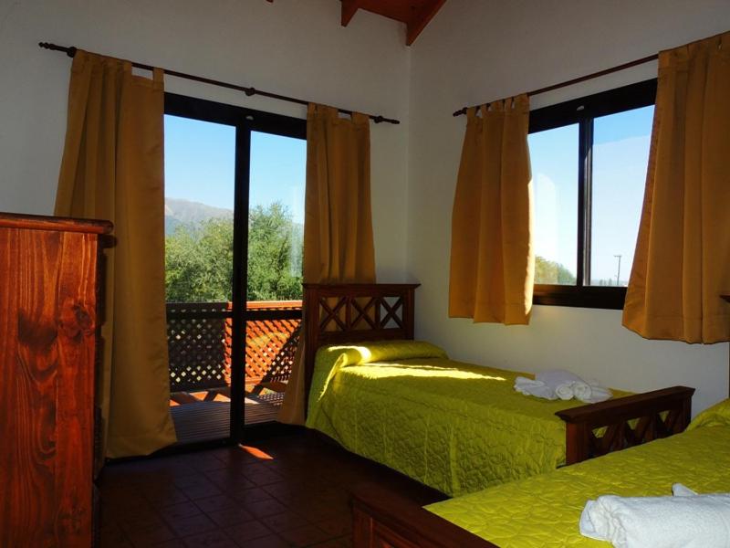 1 Schlafzimmer mit 2 Betten und einem Balkon mit Fenstern in der Unterkunft Complejo los Espinillos de Merlo in Merlo