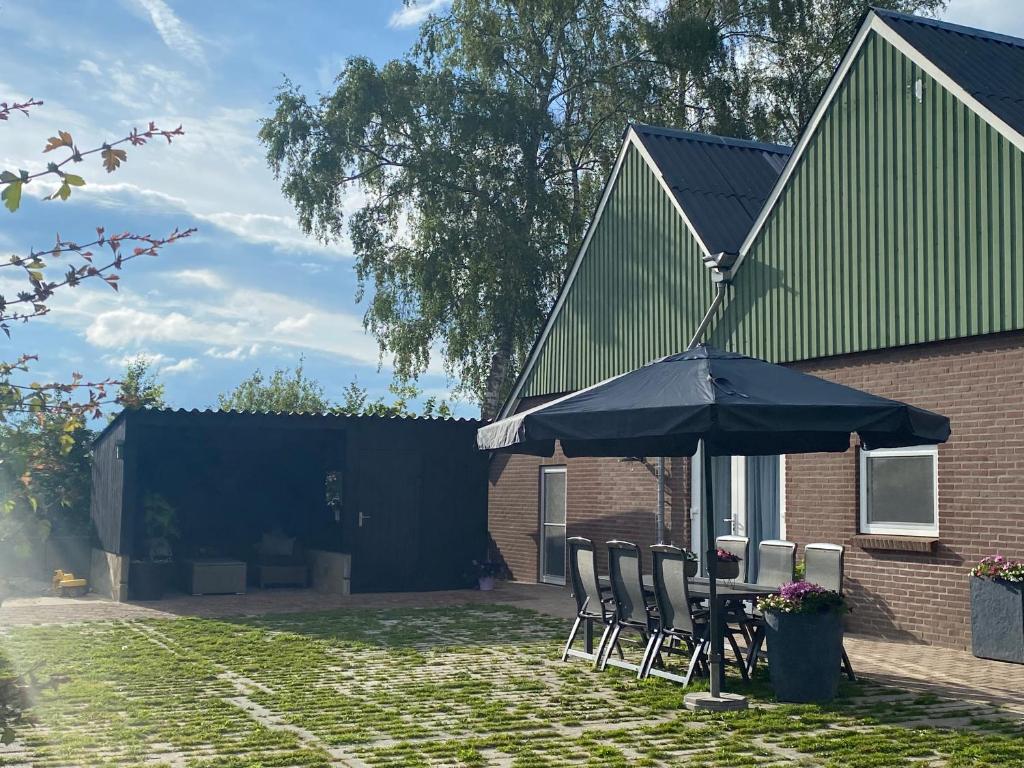 a table and chairs with an umbrella in front of a house at Vakantiewoning Op de Woerd in Aalten