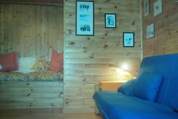 a room with a wooden wall with a bed and a couch at Estudio en Edificio Presidente in Sierra Nevada