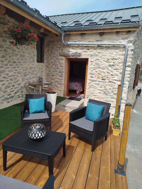 two chairs and a table on a wooden deck at Le coquelicot -Draps inclus in Val Cenis