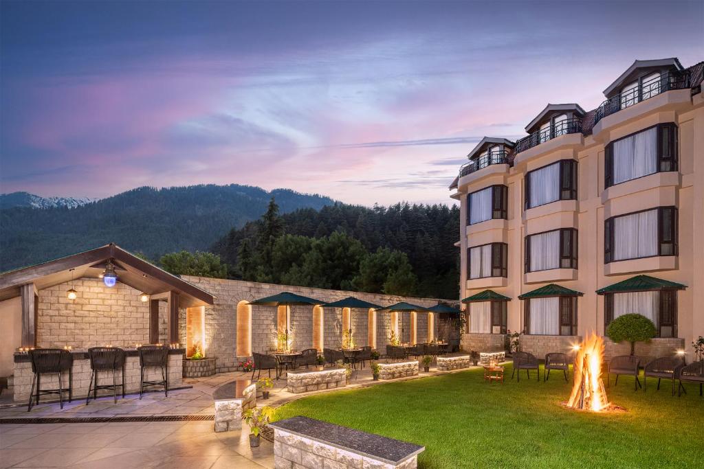 a hotel with a fire pit in the yard at Kanishka, Manali - AM Hotel Kollection in Manāli