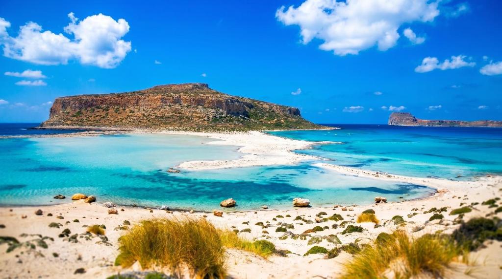 a beach with a small island in the ocean at Laskas Apartment in Stalís