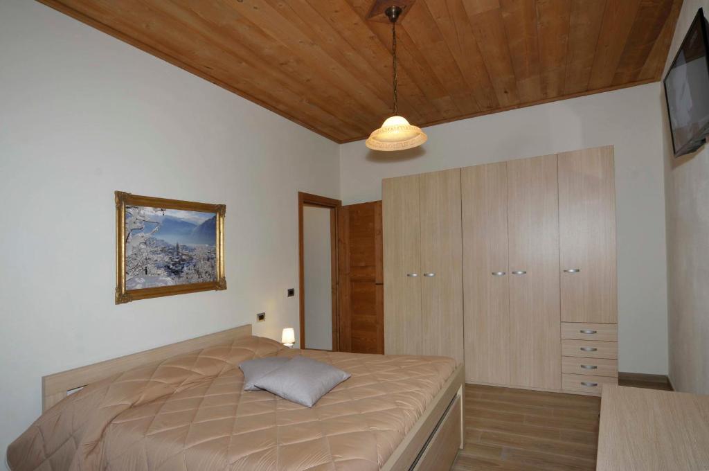 - une chambre avec un lit et un plafond en bois dans l'établissement Appartamenti Remondi, à Edolo