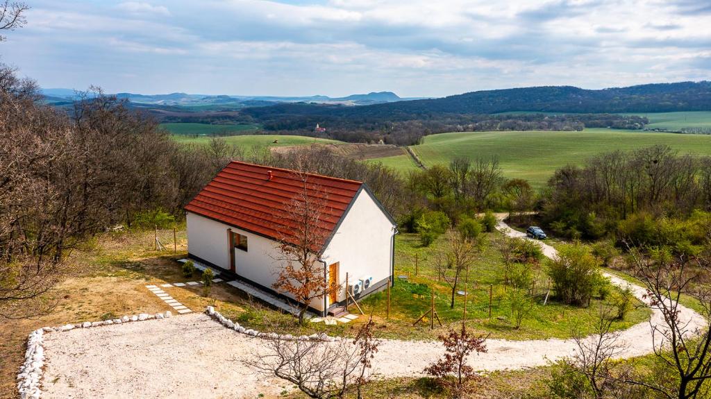 a small white house with a red roof in a field at Öreg-kő 1478 in Bajót
