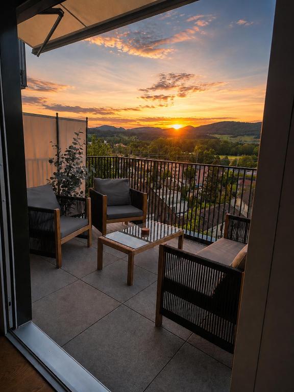 a balcony with chairs and a sunset in the background at Luxury Home JuNa in Aarau