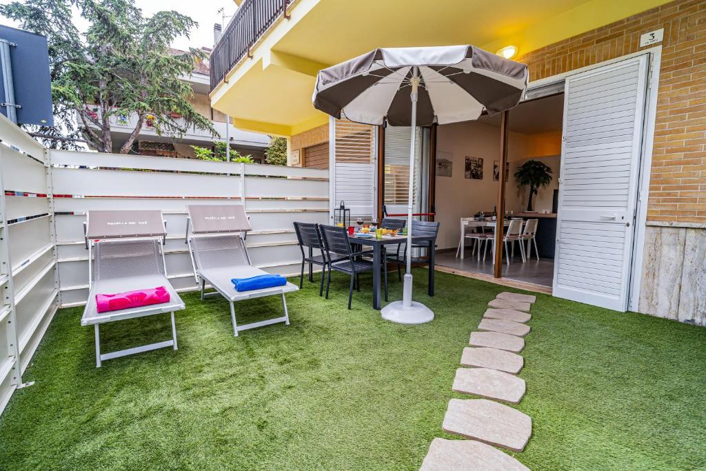 a patio with a table and chairs and an umbrella at NOVELLA DEL MAR prima fila dal mare in Grottammare