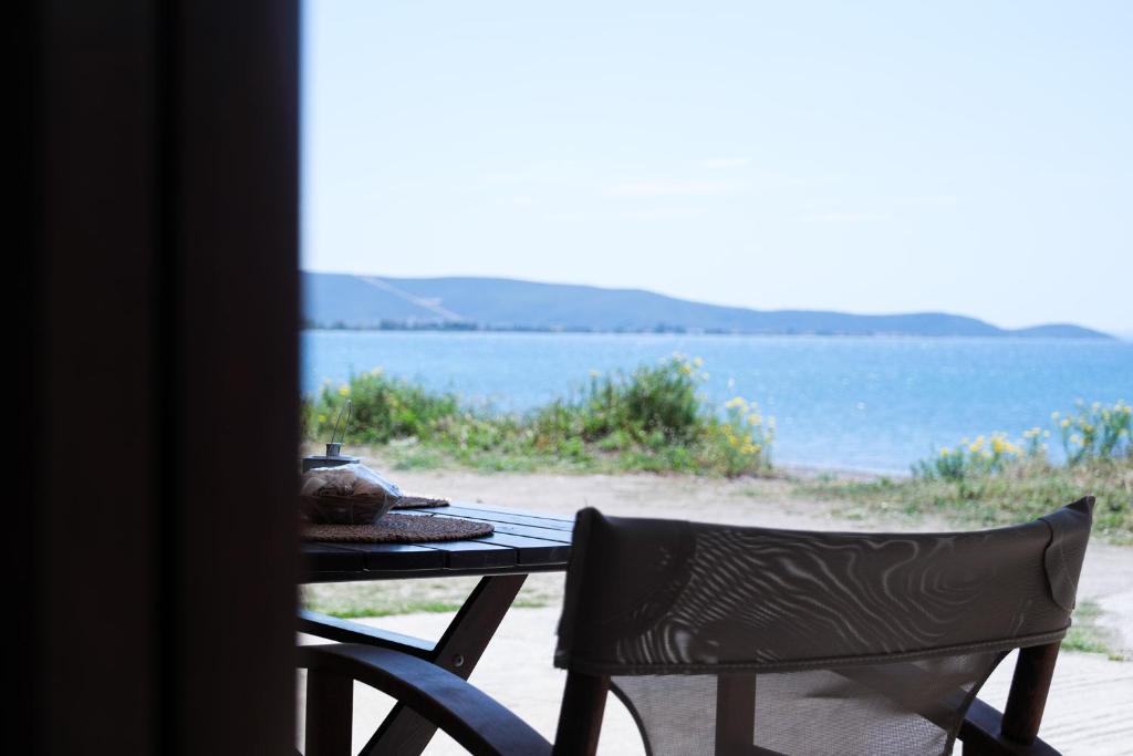 a table with a tea pot and a chair next to the ocean at Evi's House in Kandia