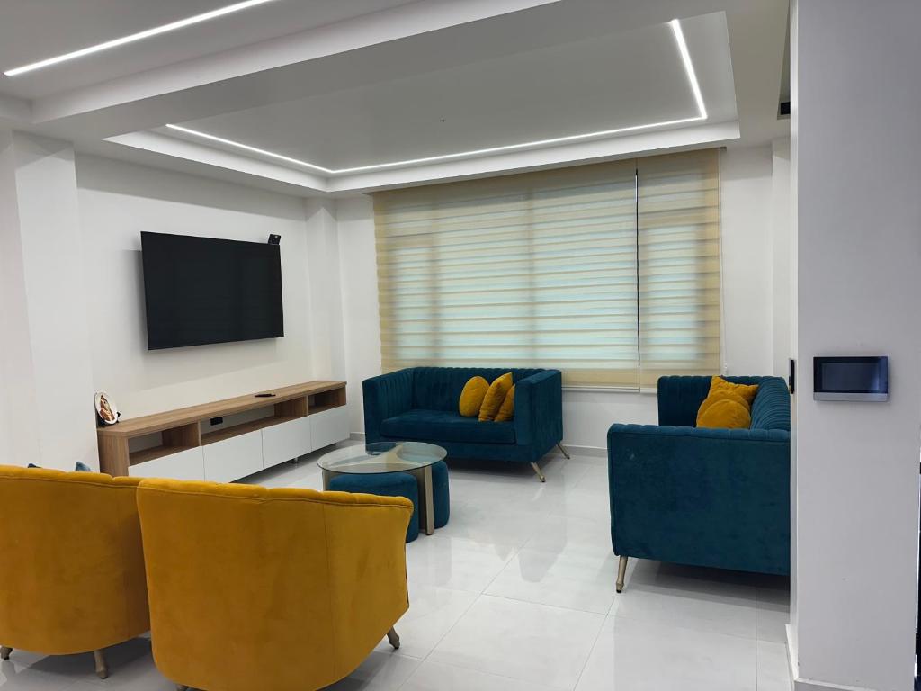 a living room with two blue chairs and a flat screen tv at DLiam Home in Baños
