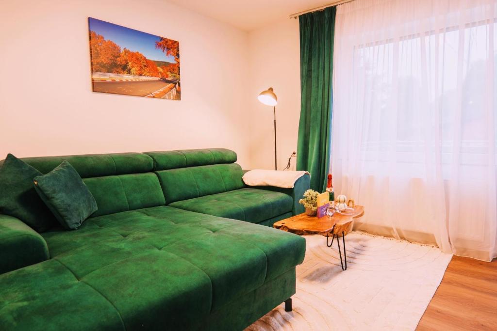 a living room with a green couch and a table at Waldblick am Ring in Kelberg