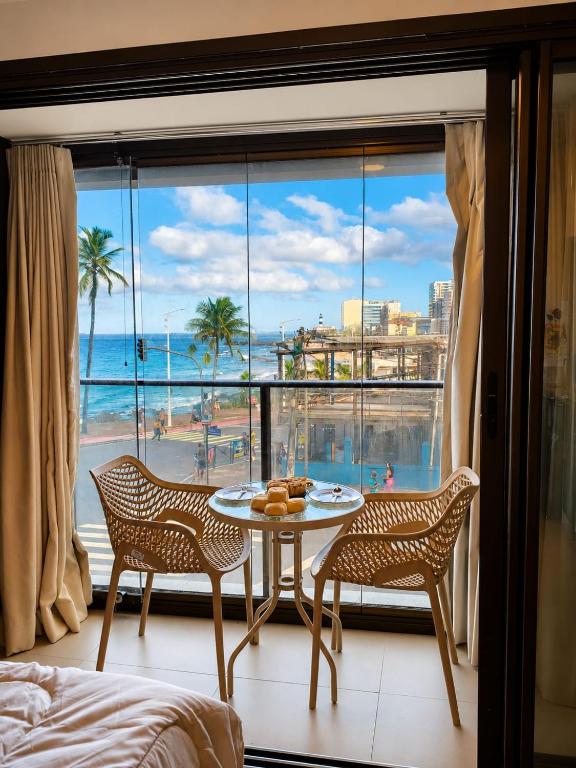a room with a table and chairs and a view of the beach at VISTA MAR SPOT Barra in Salvador