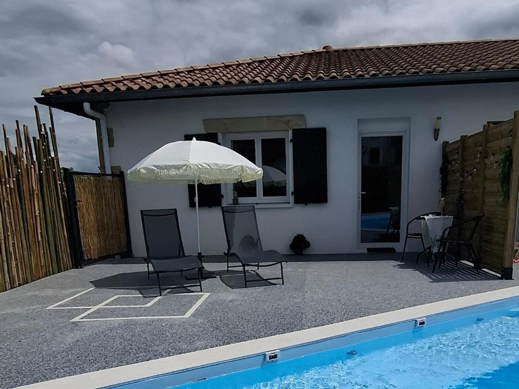 a patio with chairs and an umbrella next to a pool at Studio Coeur Basque in Iholdy