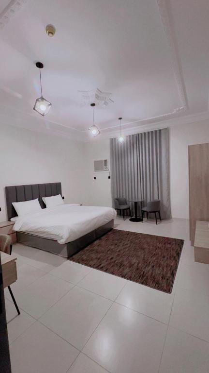 ein Schlafzimmer mit einem Bett, einem Tisch und Stühlen in der Unterkunft شقق نسائم ورد in Ta'if