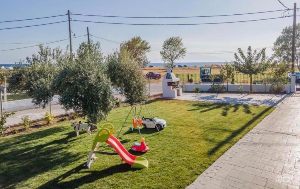 a garden with a swing in the grass at Iraklia Coral in Nea Irakleia