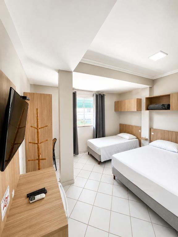 a hotel room with two beds and a flat screen tv at BURITI HOTEL Barra do Riacho Aracruz in Aracruz
