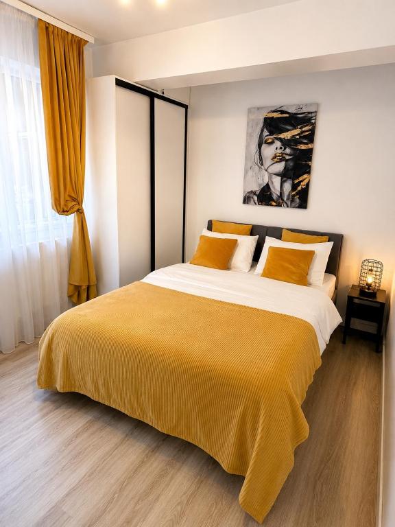 a bedroom with a large bed with a yellow blanket at Yellow Apartment in Floreşti
