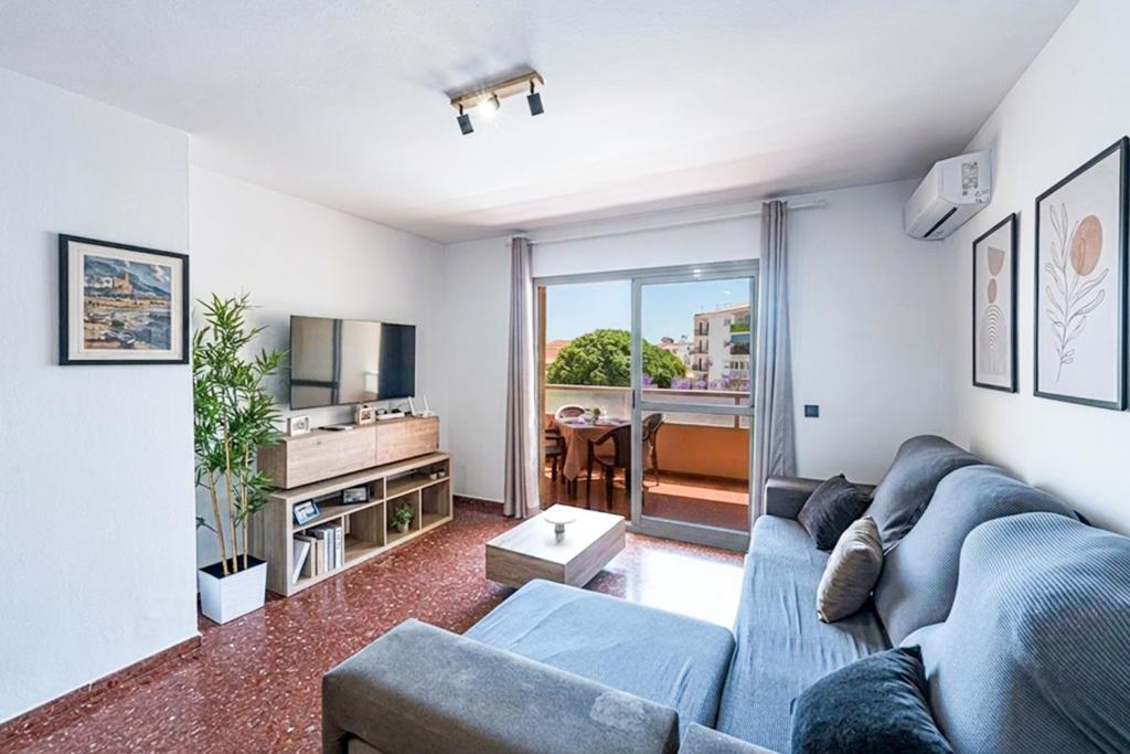 a living room with a blue couch and a tv at Bright & Spacious Apartment in Nerja Centre in Nerja