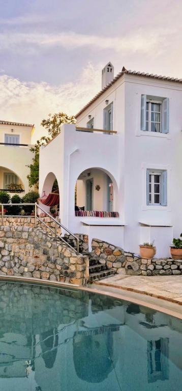 a white house with a swimming pool in front of it at Villa Giasemi in Spetses