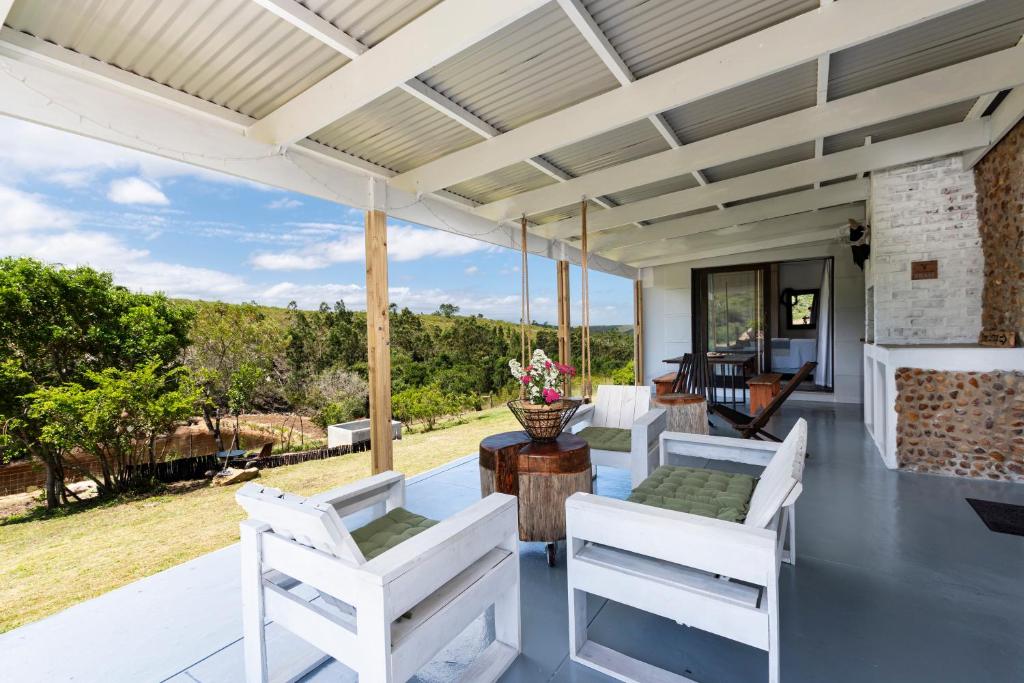 an outdoor patio with white chairs and a table at Fungamukaba Sanctuary in Mossel Bay