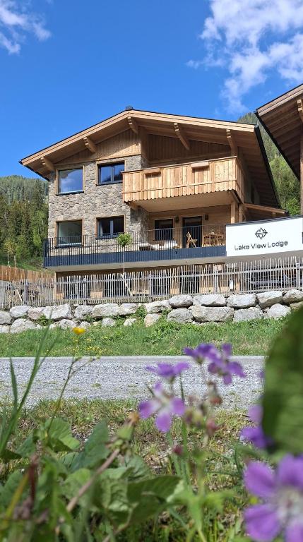 a house with a fence and flowers in front of it at Lake View Lodge in Flachau